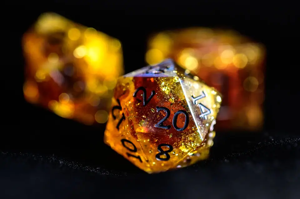 Close-up of amber resin polyhedral dice with glitter inside, lit against a dark background